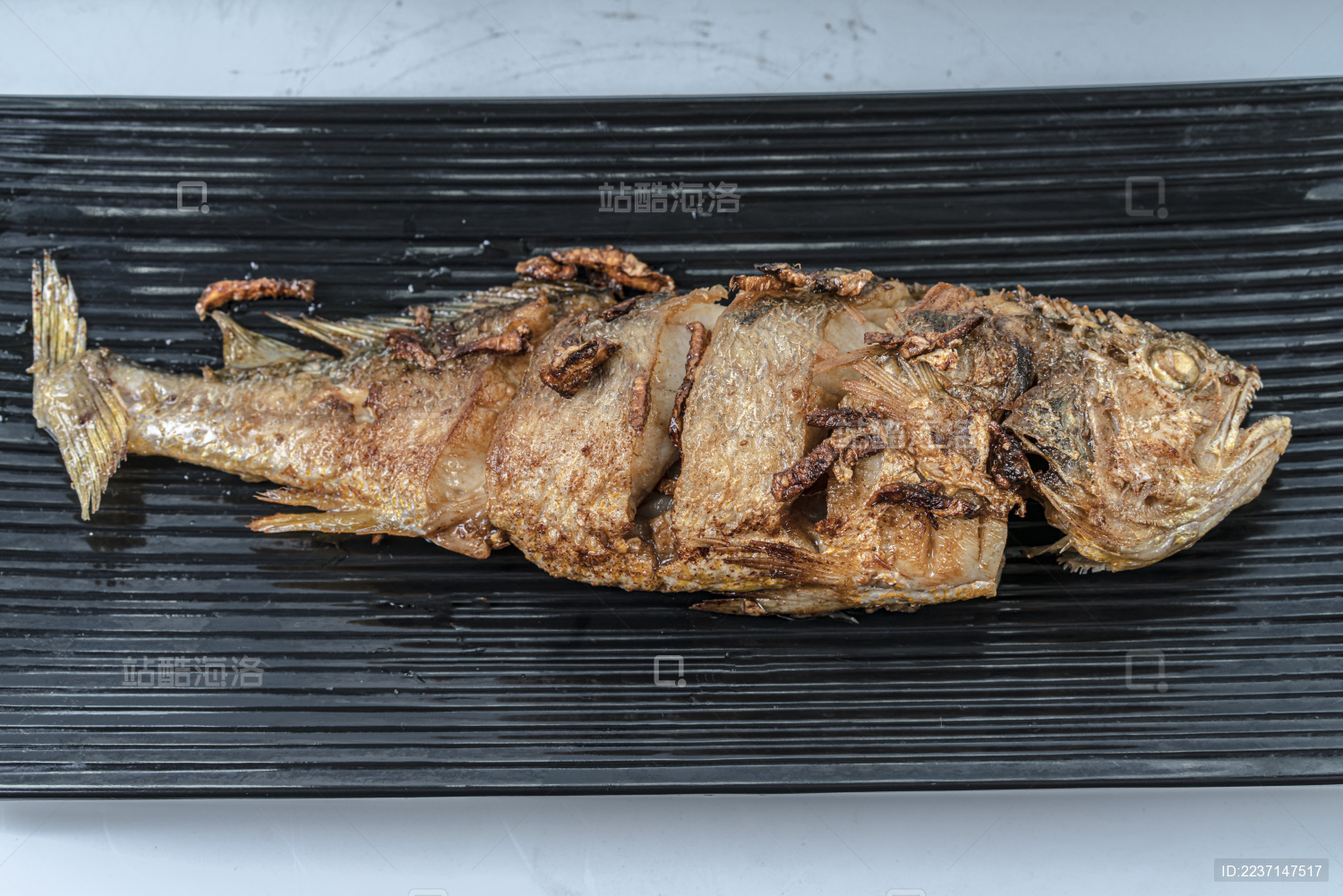 一条煎好的鱼放在长条形的黑色盘子上