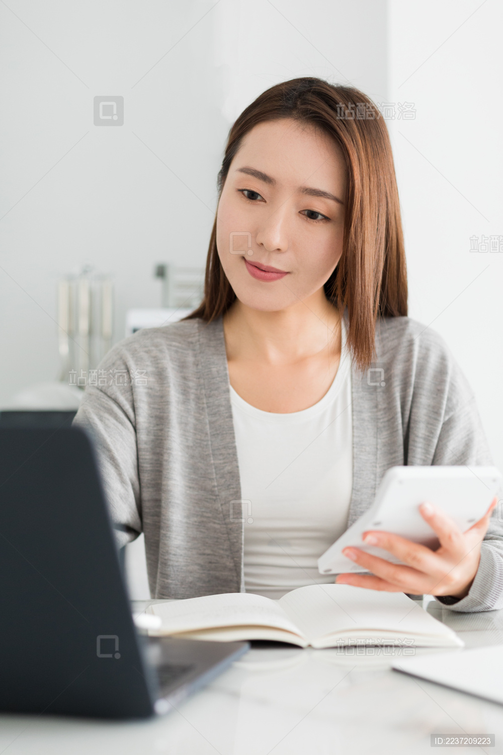 年轻东方女性在使用电脑和计算器