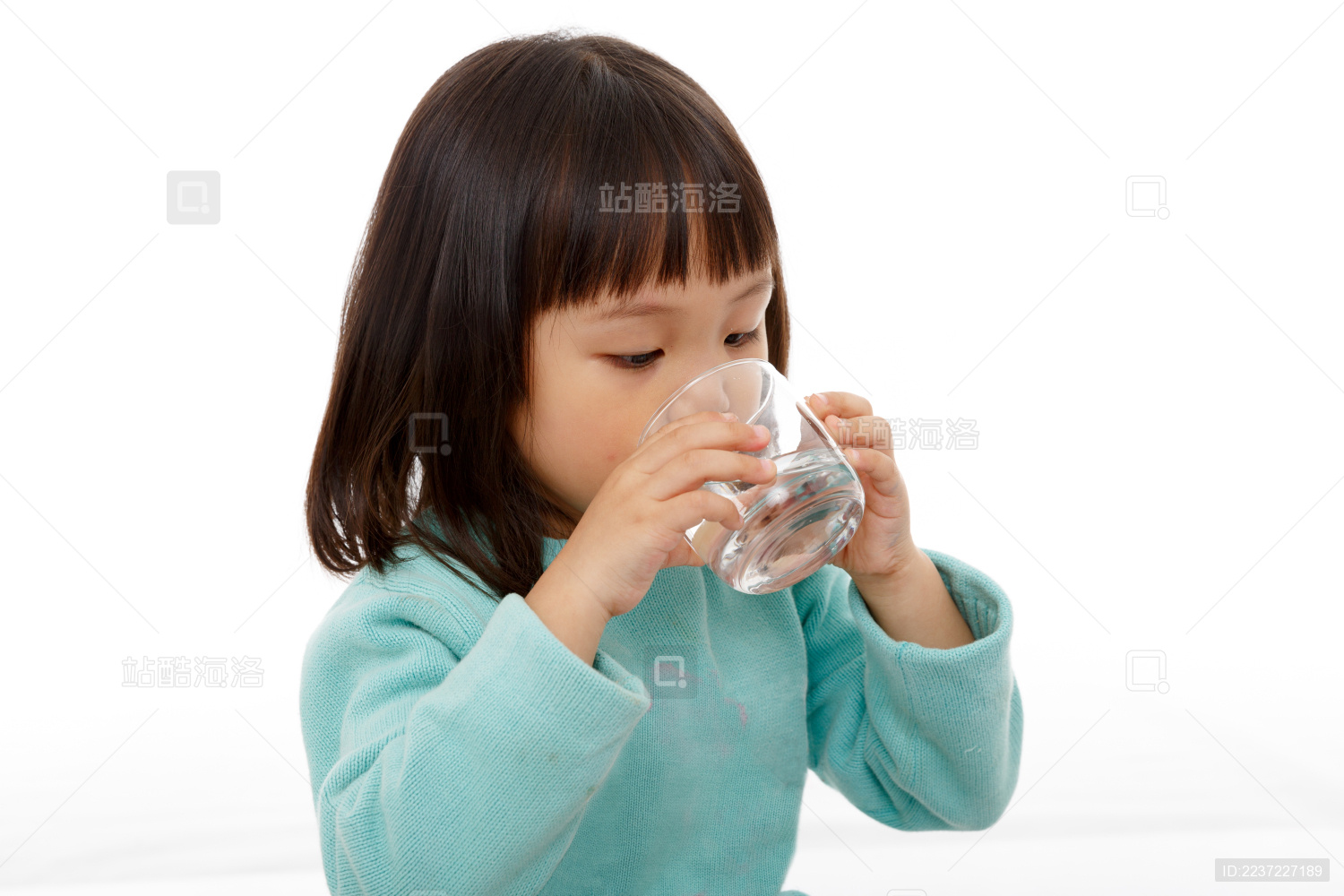 手捧着玻璃杯喝白开水的小女孩