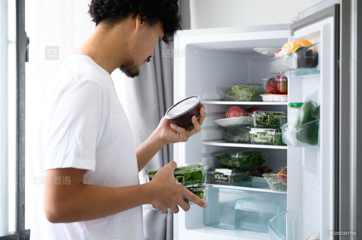 年轻亚洲男人从冰箱里拿食材