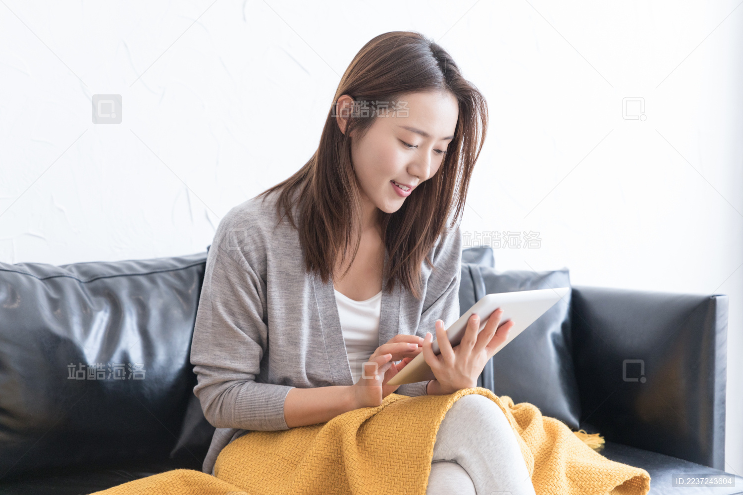 一名年轻女性坐在沙发上使用平板电脑