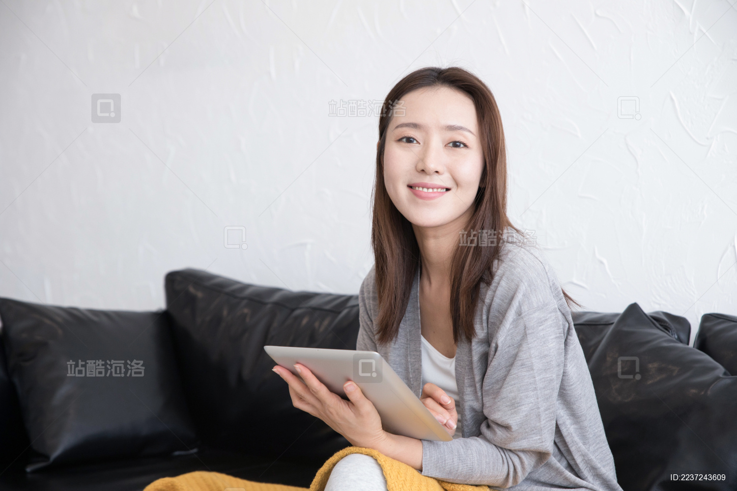 一名年轻女性坐在沙发上使用平板电脑