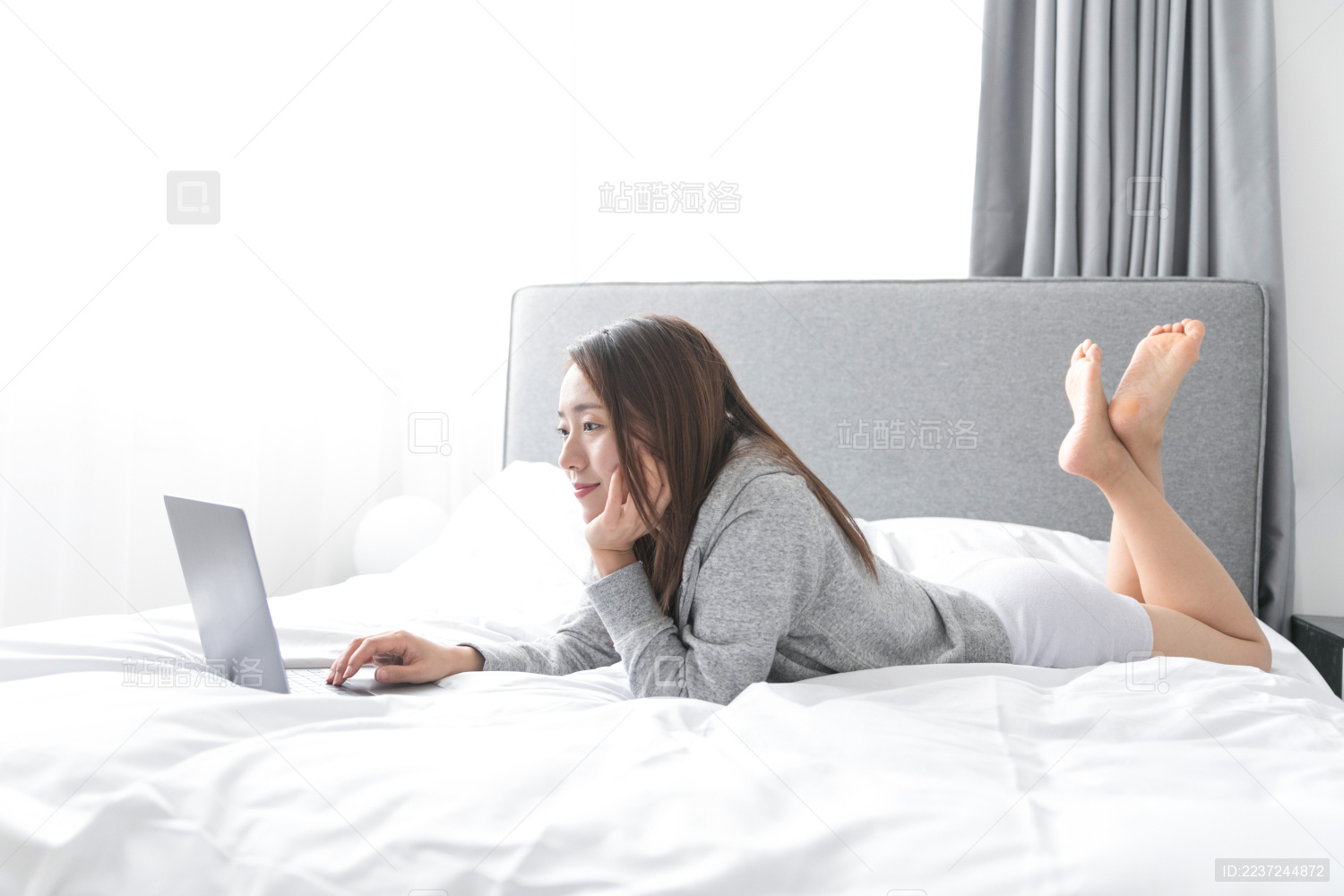 一名年轻女性在床上玩笔记本电脑