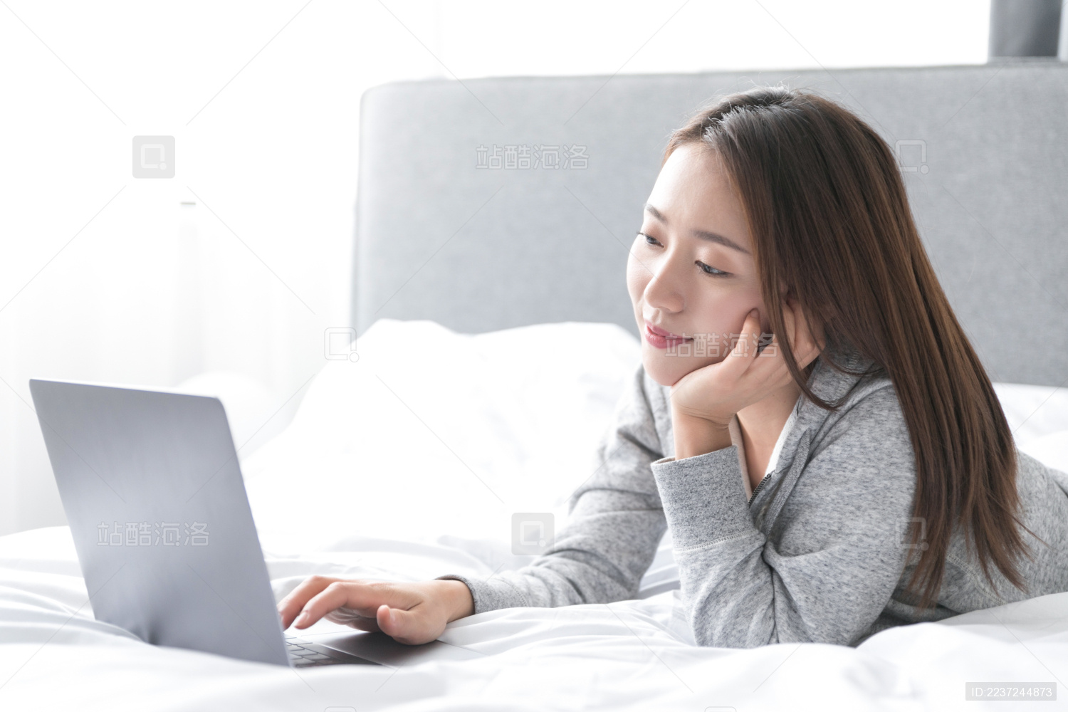 一名年轻女性在床上玩笔记本电脑