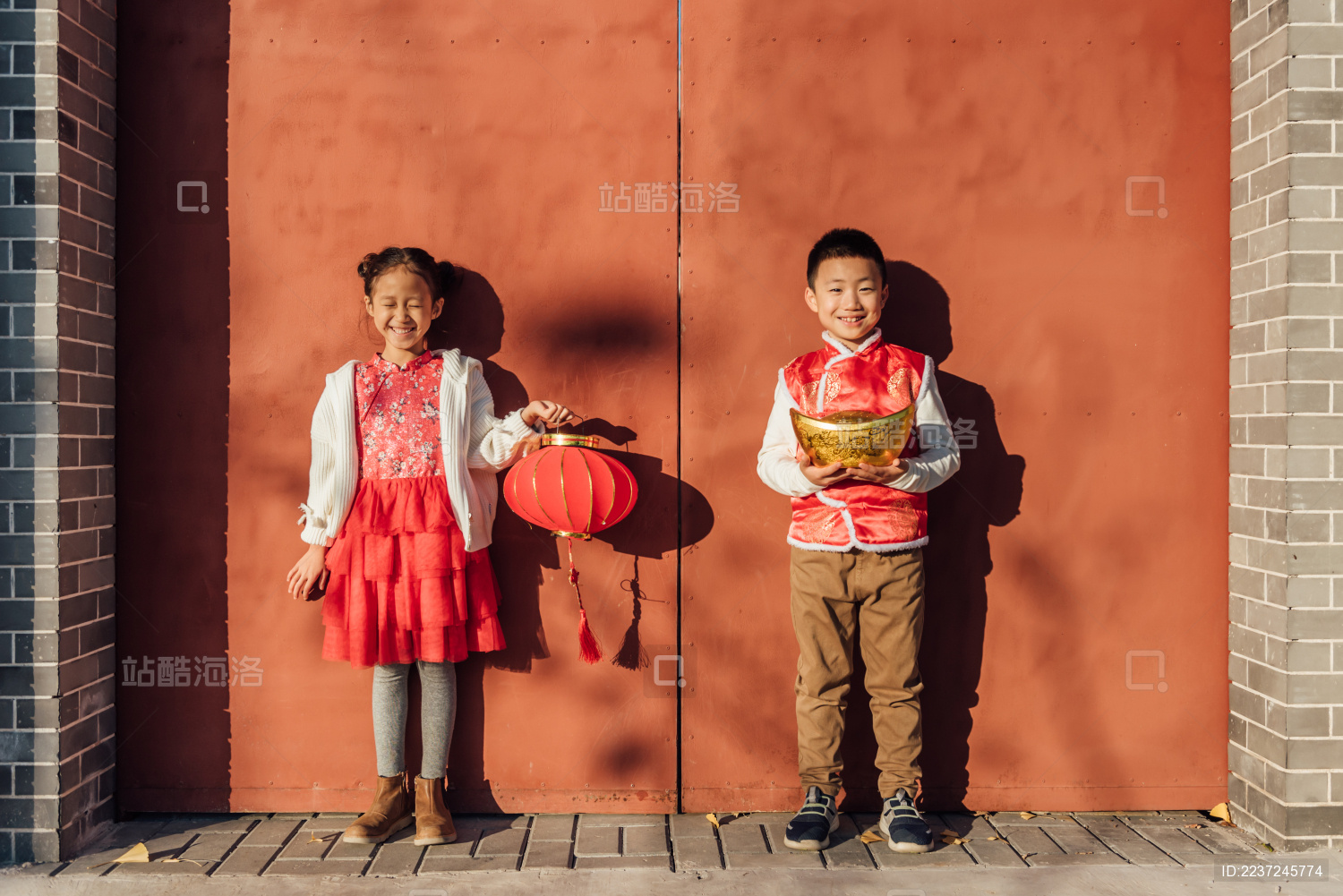 一男一女两个小孩儿在大门口拿着灯笼
