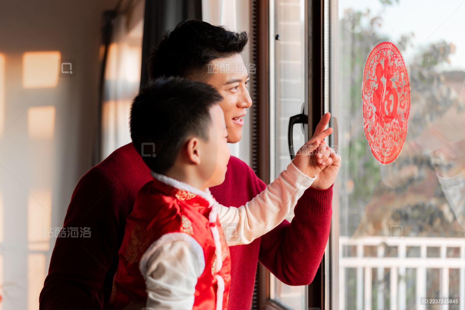 一对父子在屋内正在贴窗花