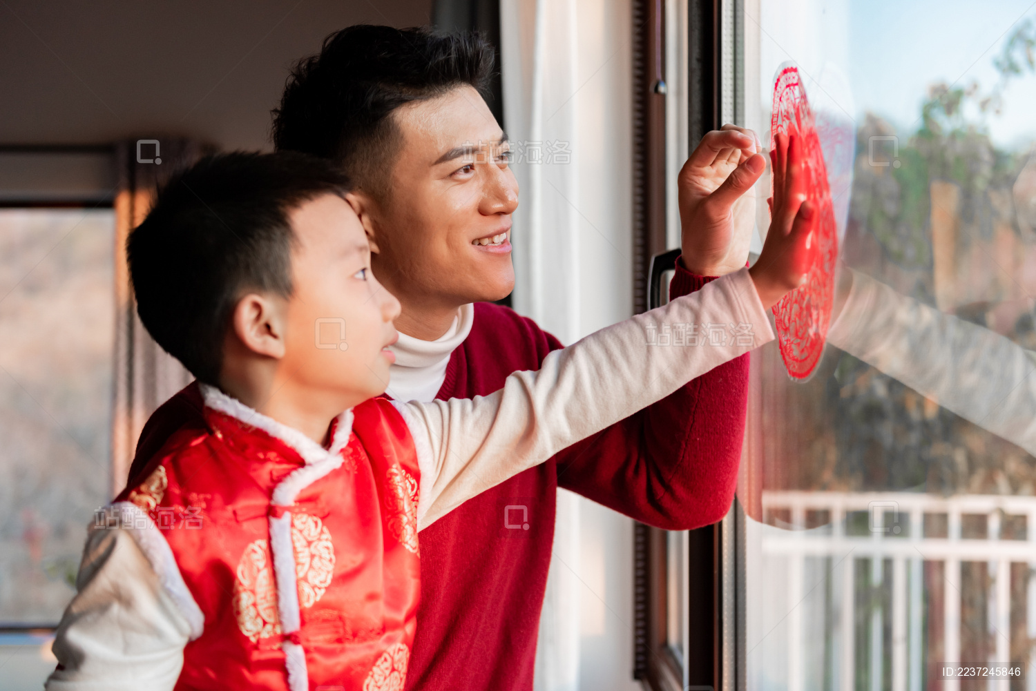 一对父子在屋内正在贴窗花