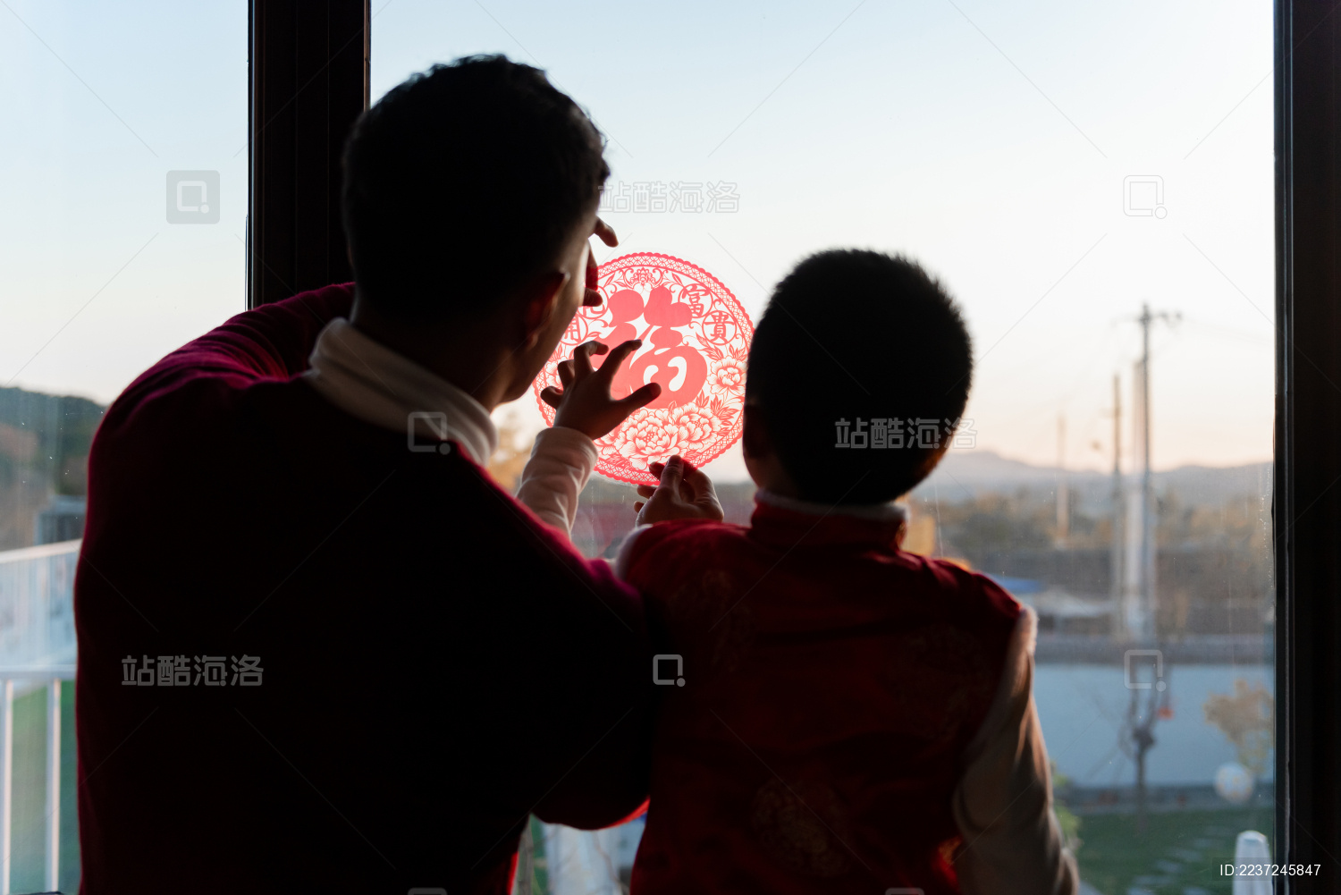 一对父子在屋内正在贴窗花