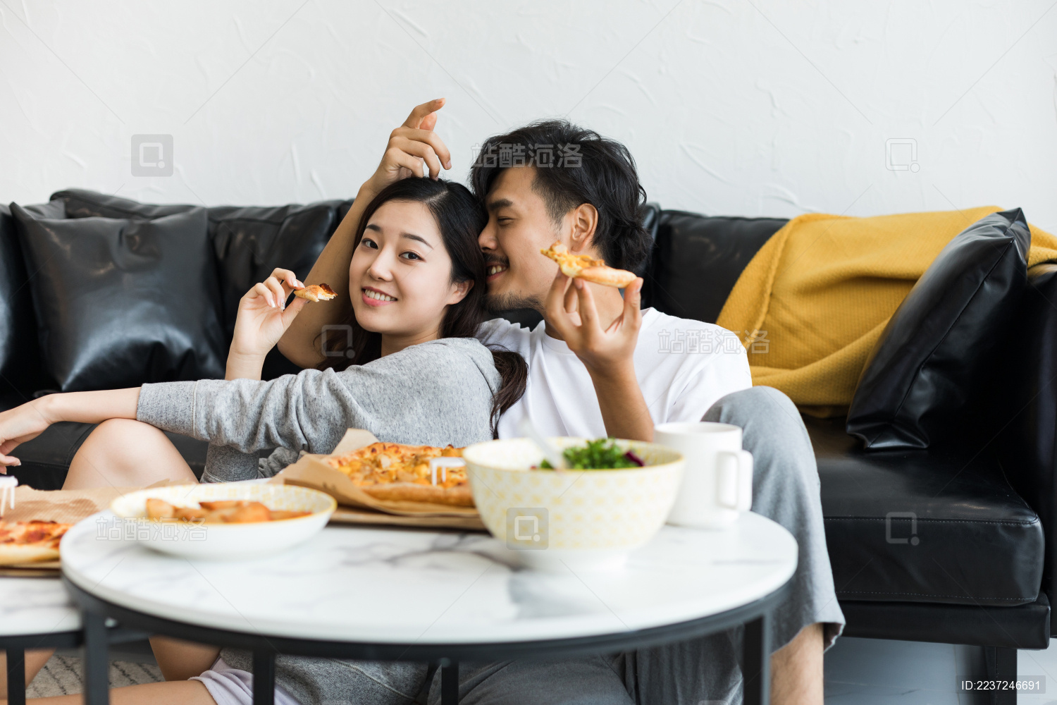 年轻情侣在客厅坐着吃披萨外卖