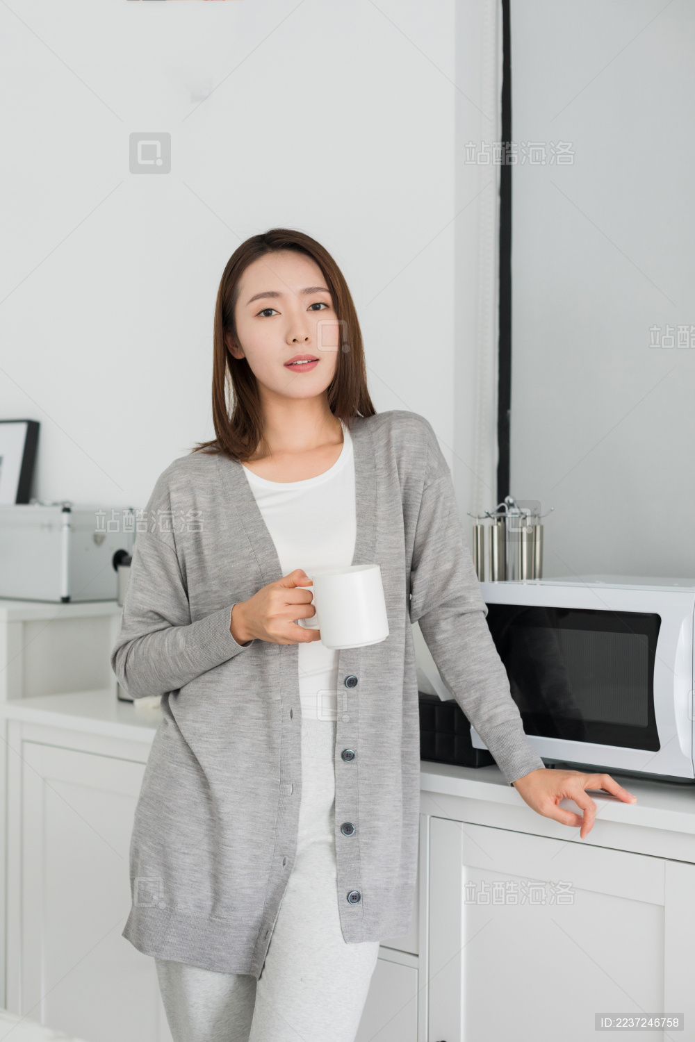 年轻女性拿着水杯站在餐桌旁边
