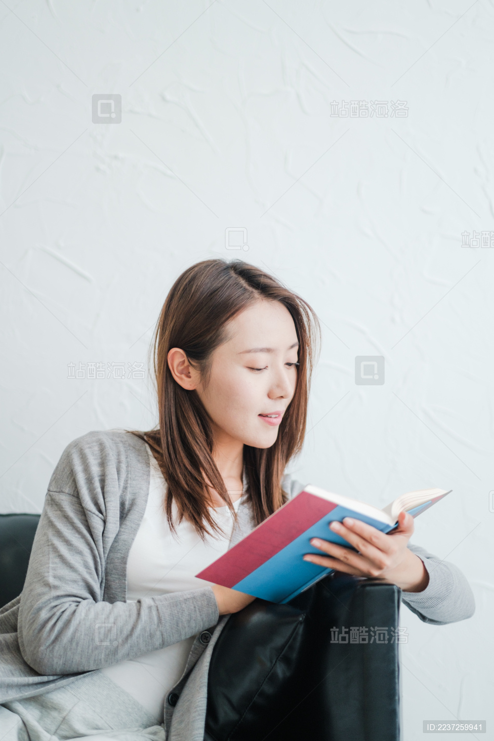 年轻漂亮女孩坐在沙发上看书