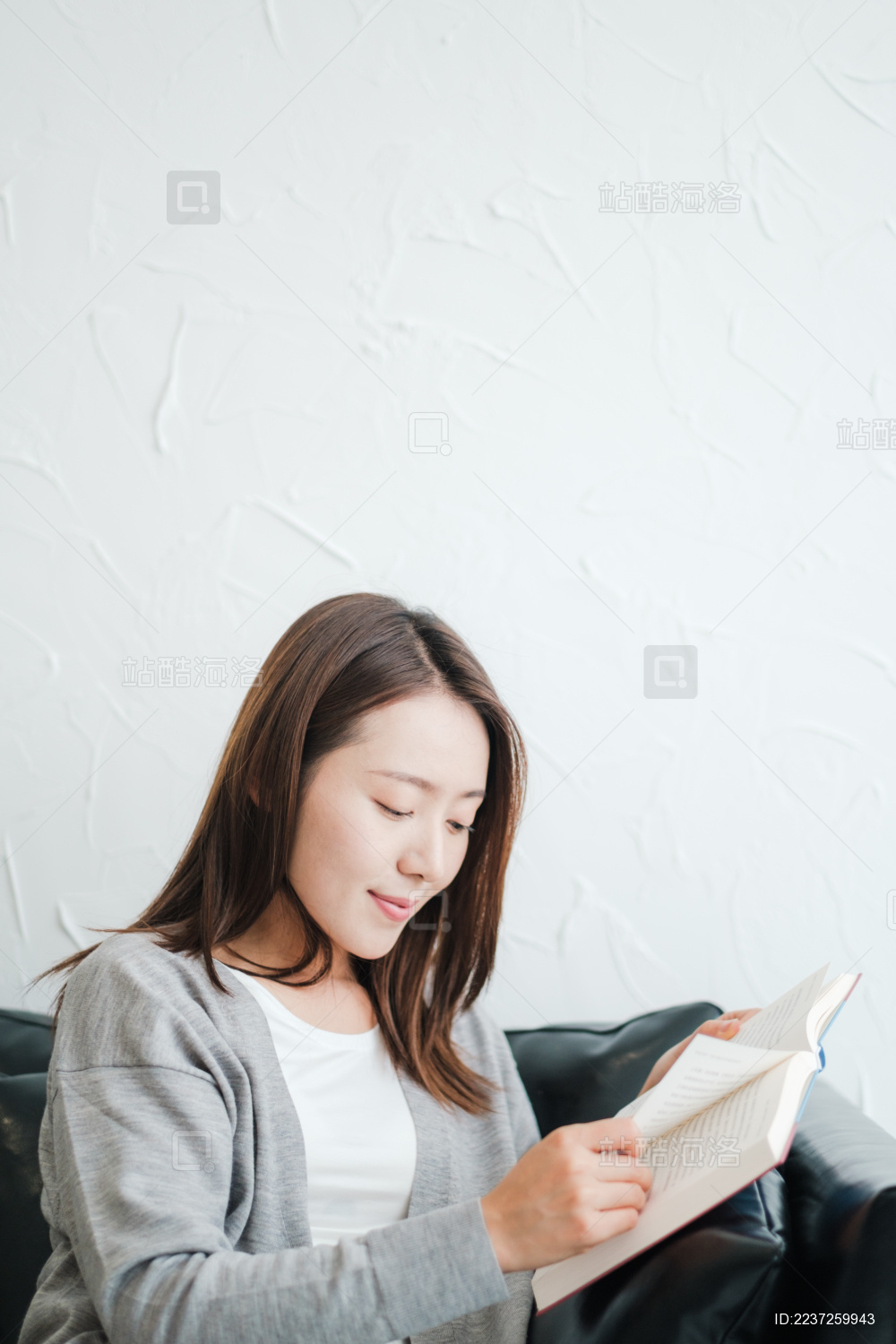 年轻漂亮女孩坐在沙发上看书