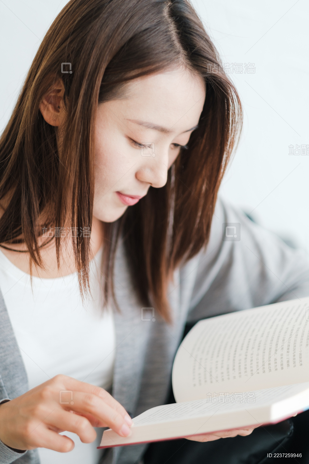 年轻漂亮女孩坐在沙发上看书