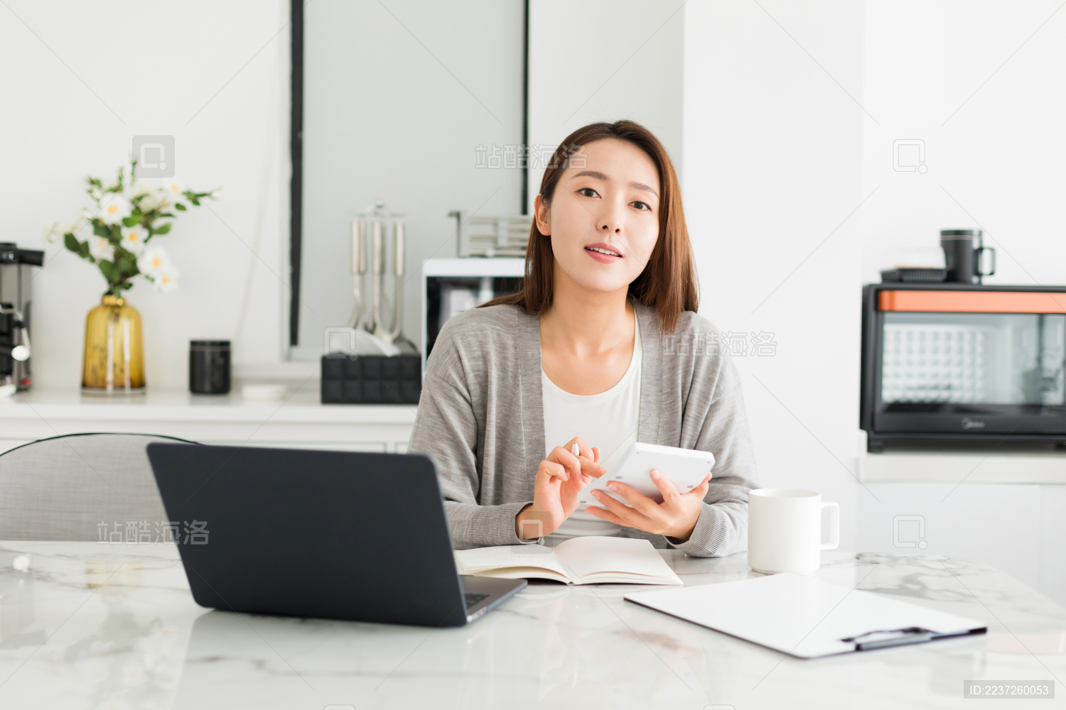 一个年轻女性坐在电脑工作看镜头