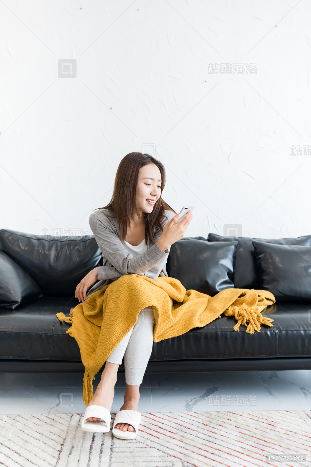 一个年轻女性坐在沙发上看手机