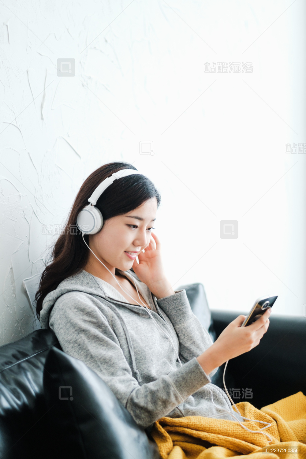 年轻漂亮女孩坐在沙发上听音乐