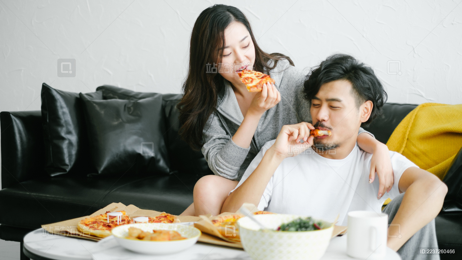 年轻情侣在客厅沙发前一起吃披萨