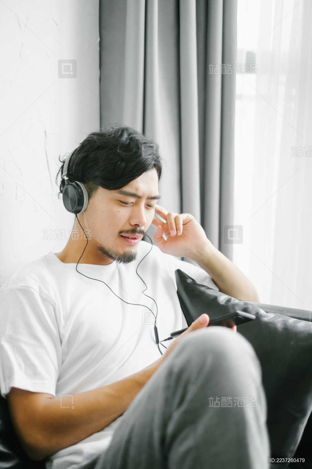 年轻帅气男人坐在沙发上听音乐