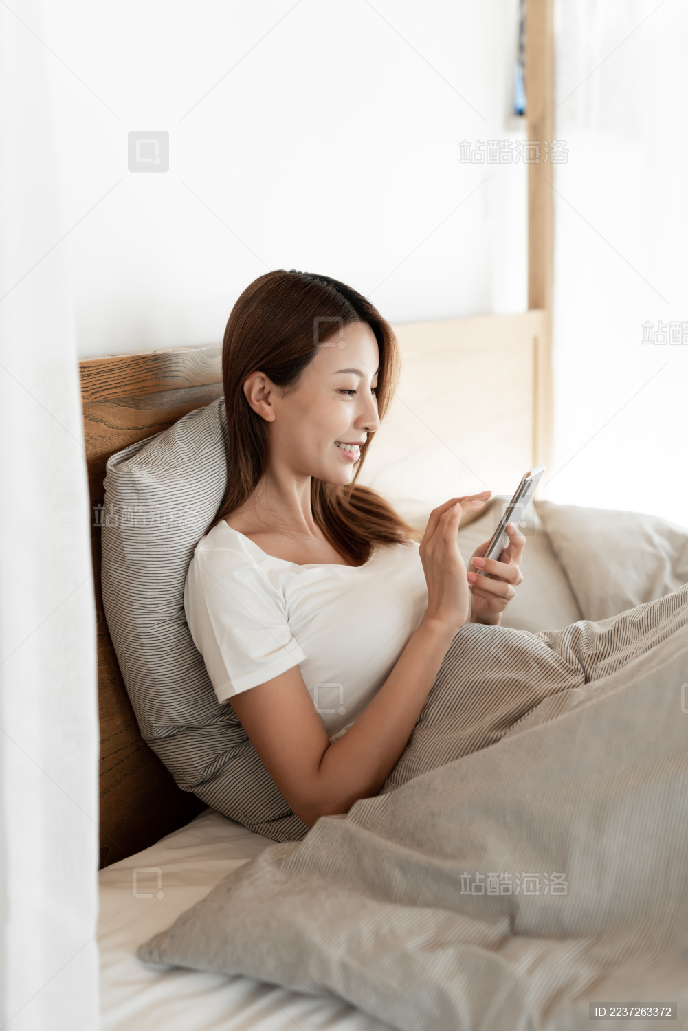 一位年轻女性在床上使用手机