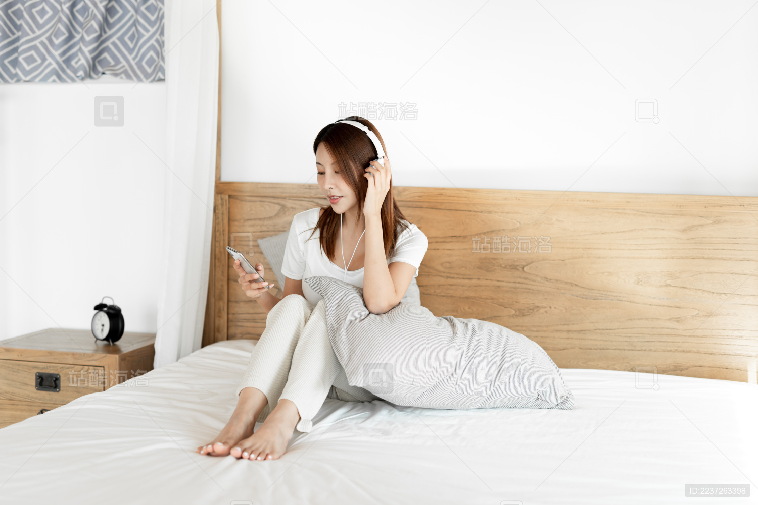 一位年轻的女性在床上戴着耳机享受音乐