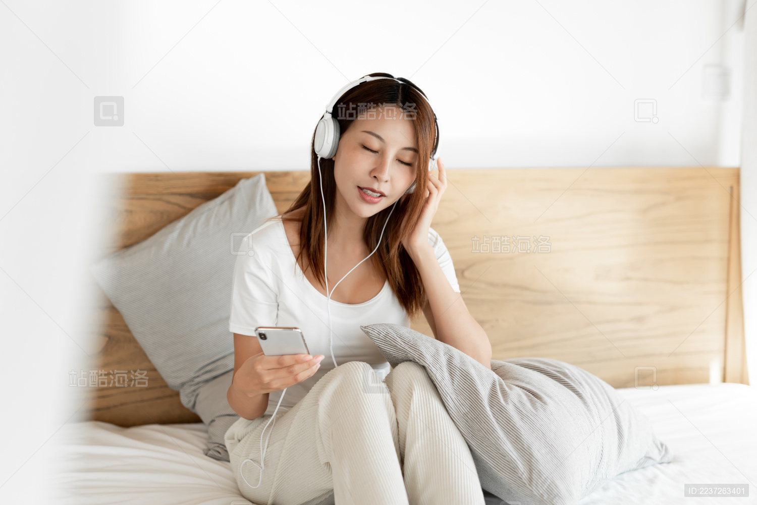 一位年轻的女性在床上戴着耳机享受音乐