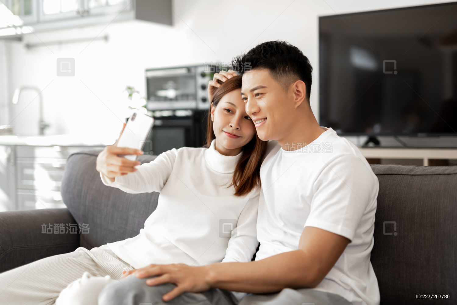 一对情侣正在沙发上使用手机拍照和自拍