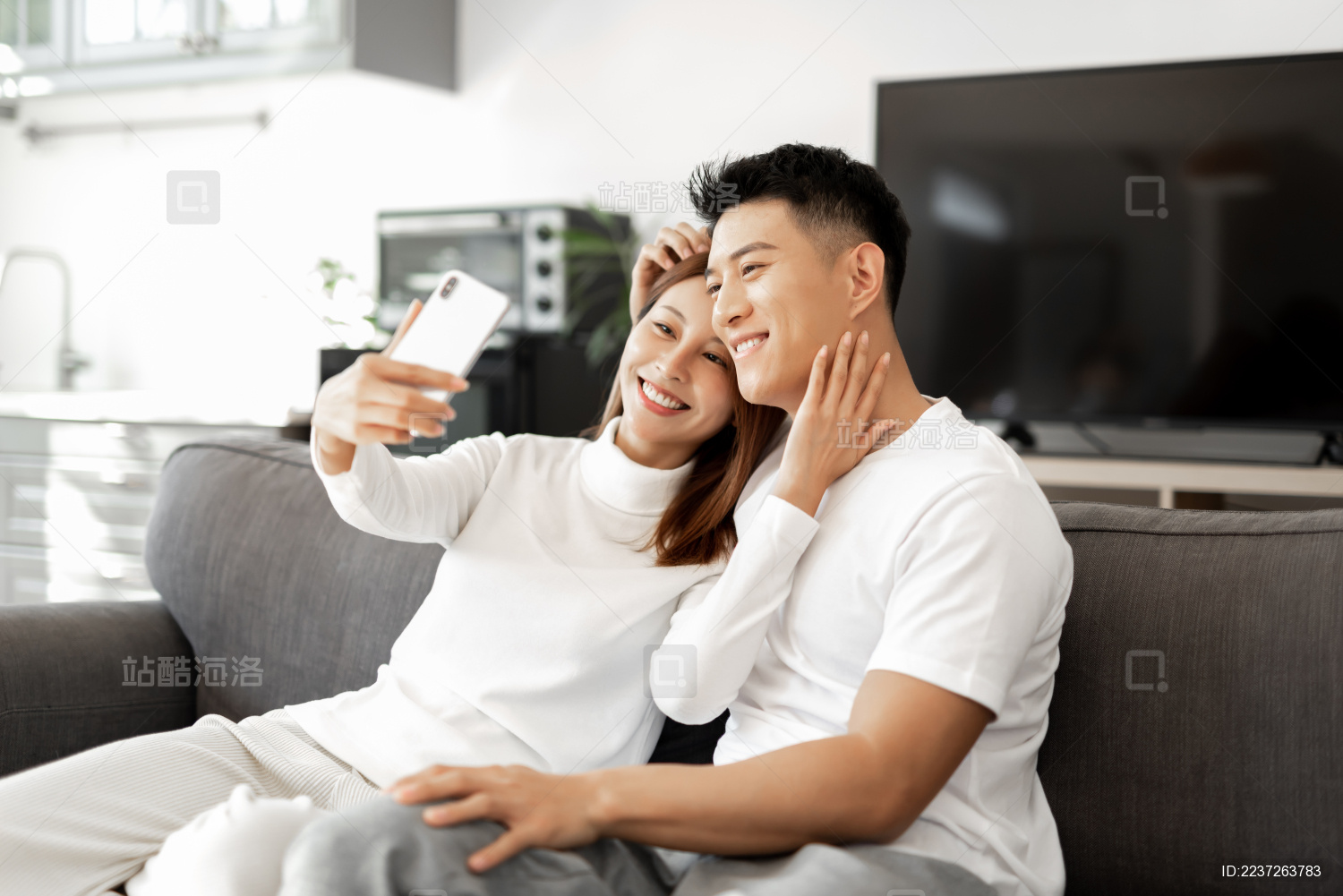 一对情侣正在沙发上使用手机拍照和自拍