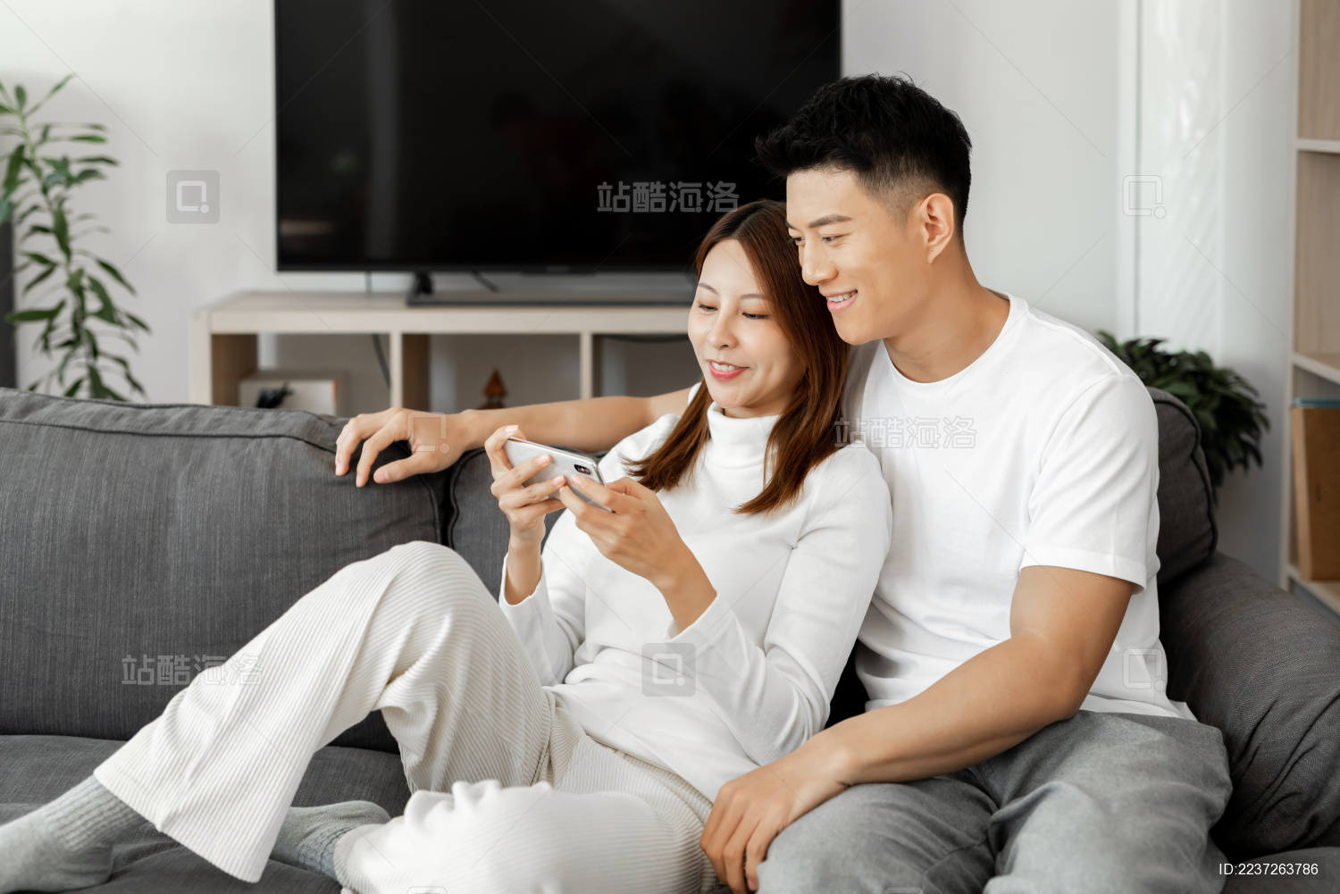 一对情侣正在沙发上使用手机拍照和自拍