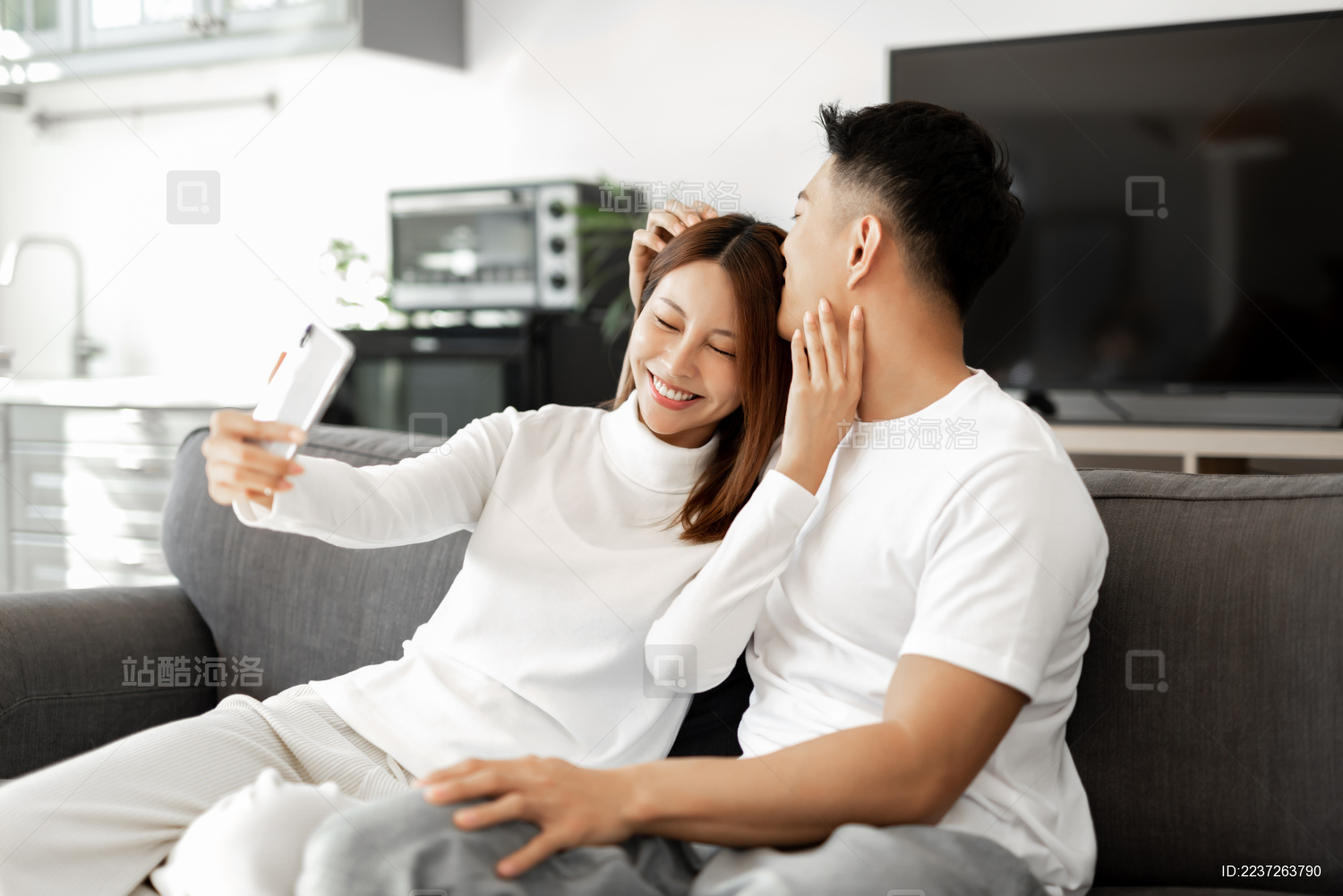 一对情侣正在沙发上使用手机拍照和自拍