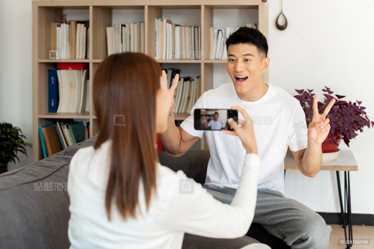 一对情侣正在沙发上使用手机拍照和自拍