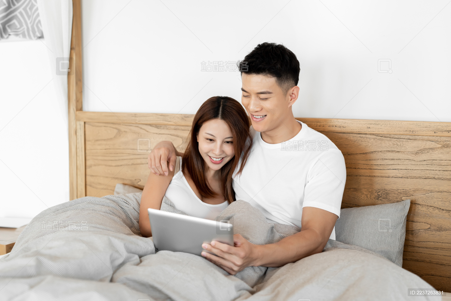 一对情侣在床上开心的使用平板电脑