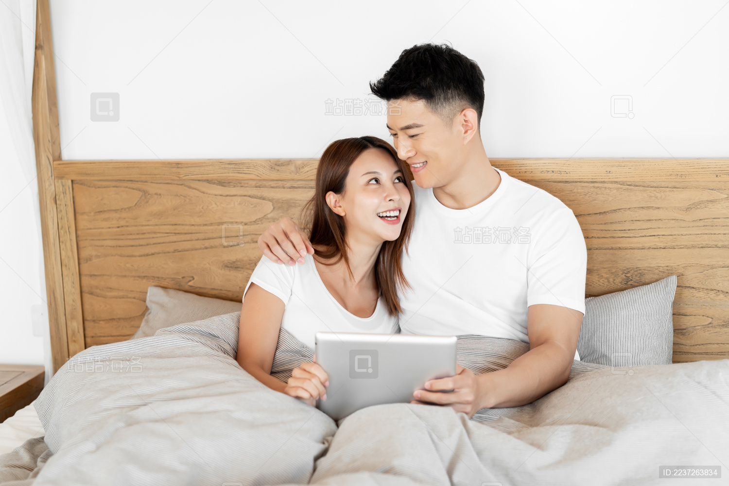 一对情侣在床上开心的使用平板电脑