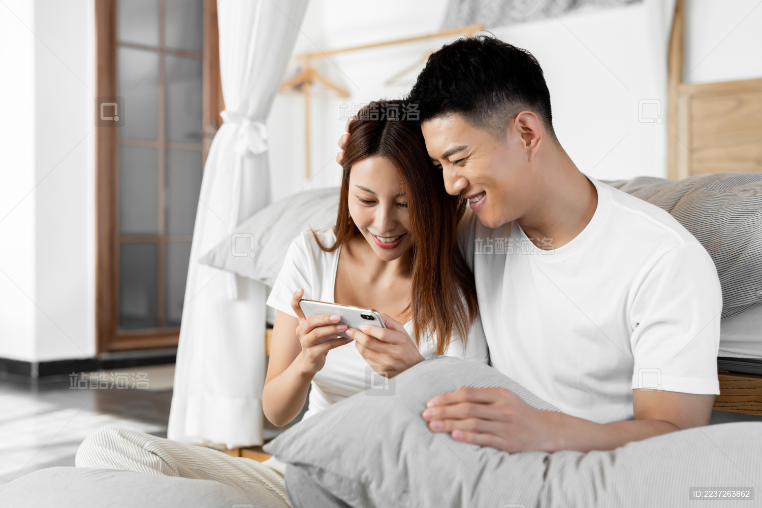 一对情侣正在床前开心的用手机购物