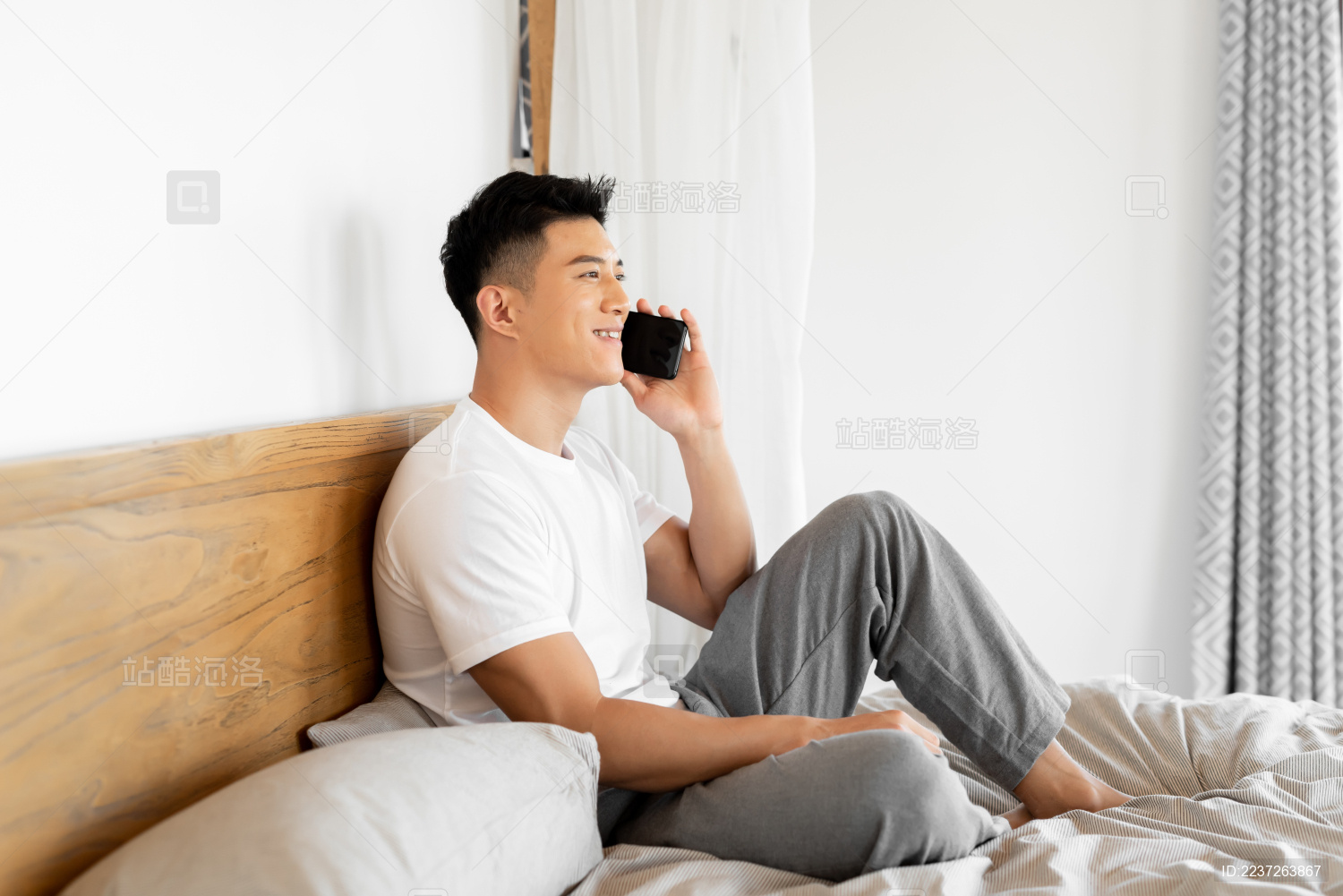 一个年轻的男性正在床上打电话