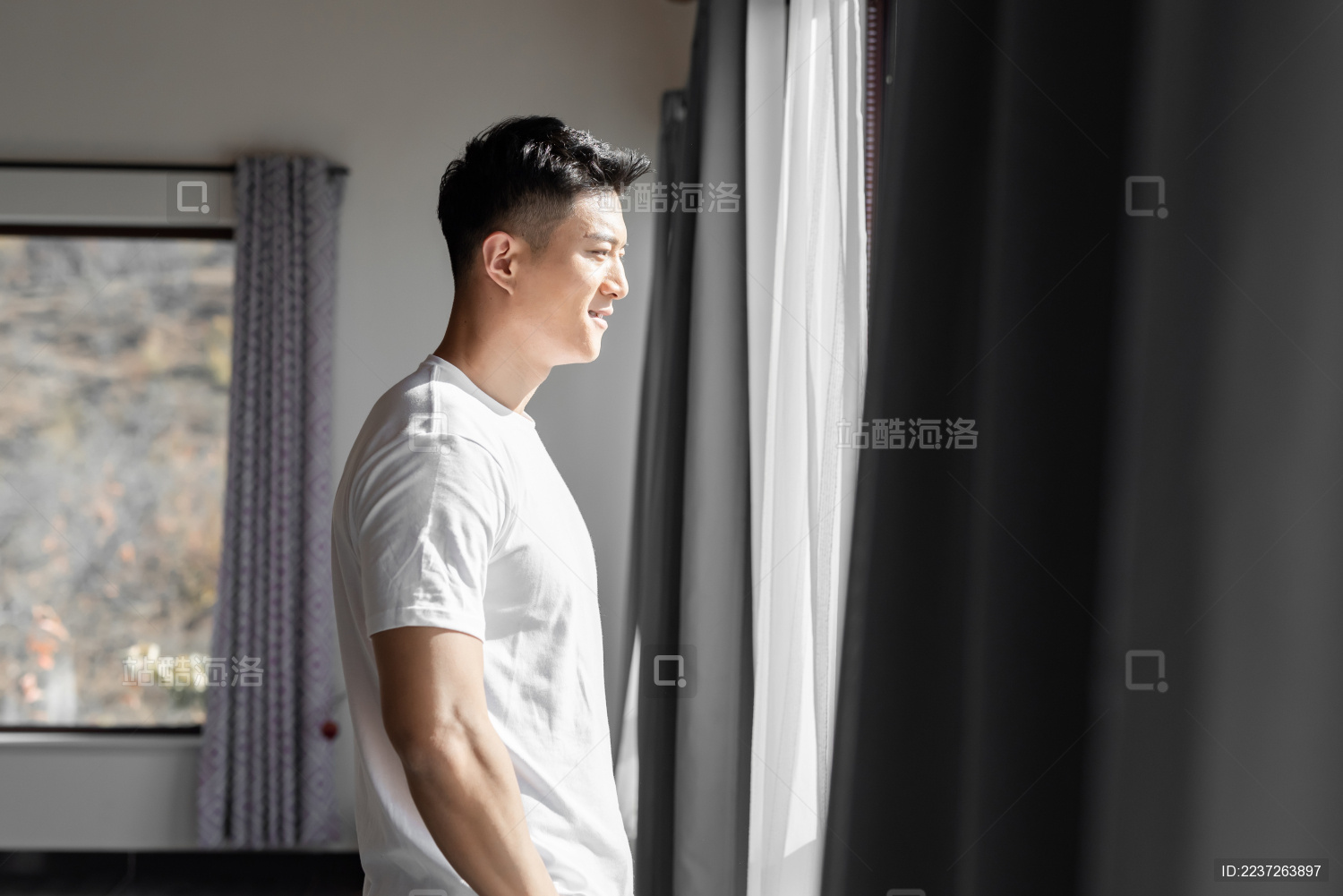 一位年轻的男性起床后站在窗前