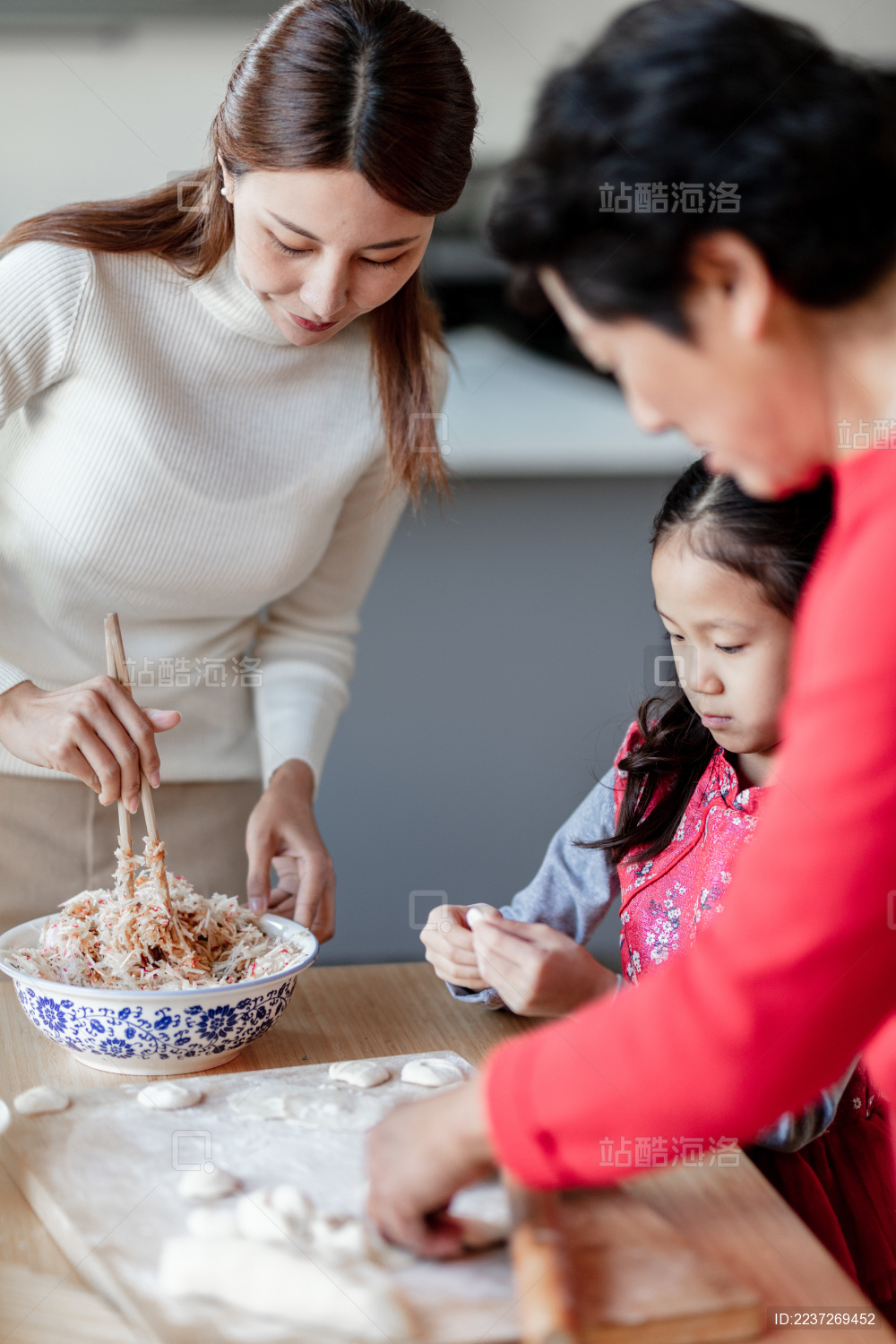 奶奶和妈妈在教小女孩包饺子