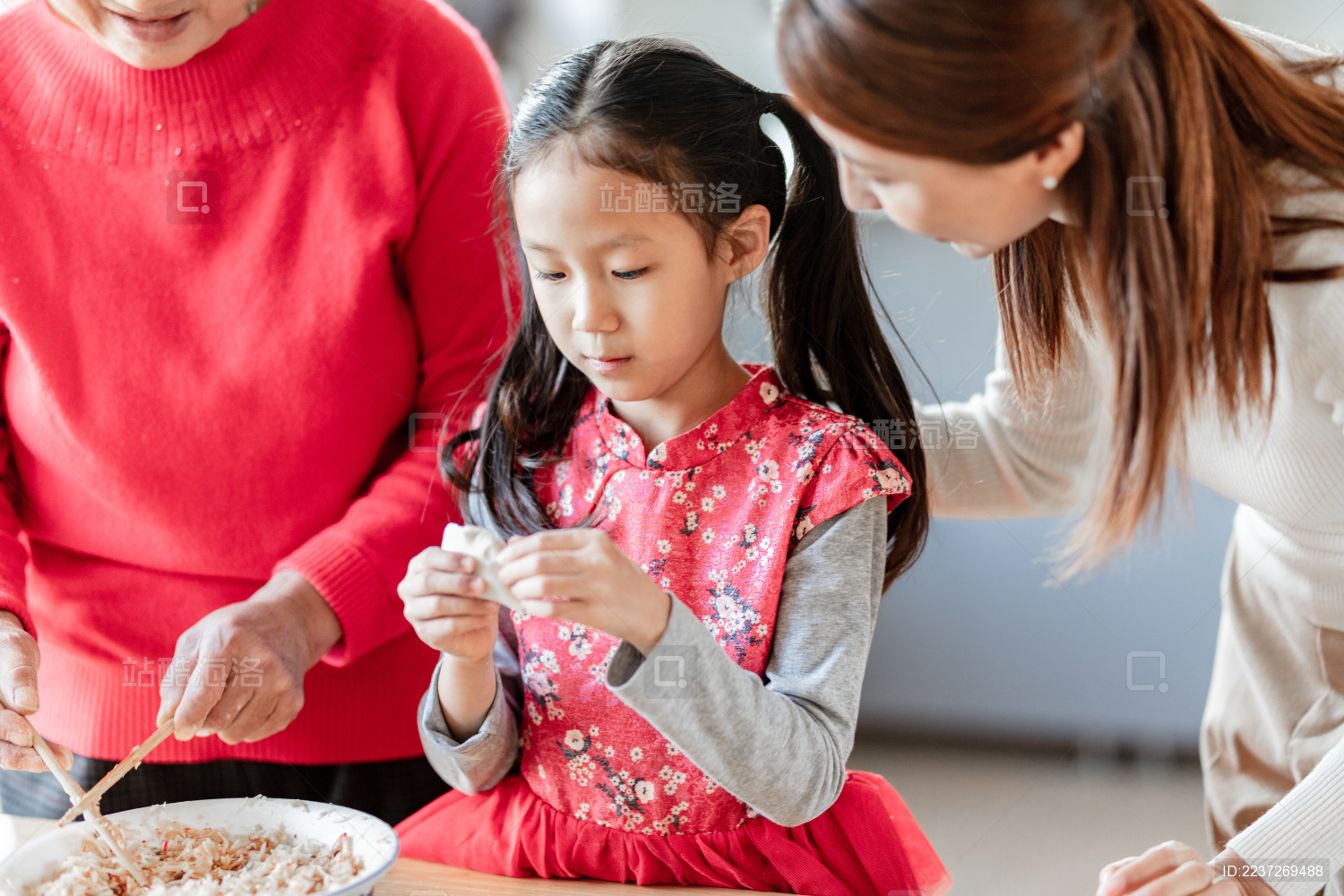 奶奶和妈妈在教小女孩包饺子