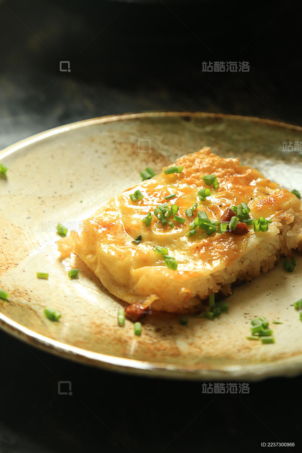 黑背景上黄褐色盘子中的一块三鲜豆皮 上面撒着葱花