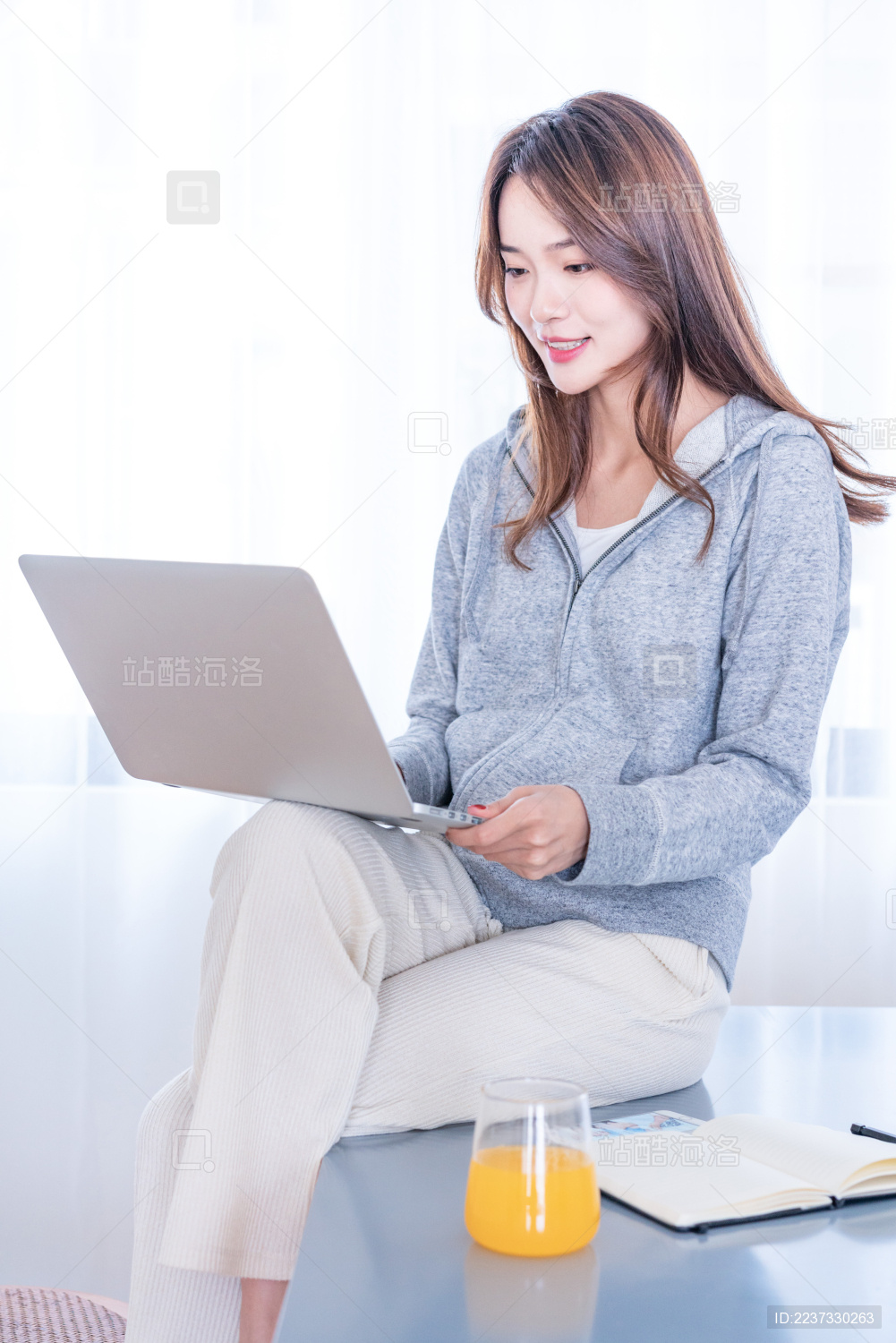 一名年轻的亚洲女子在坐在餐厅一边吃早餐一边