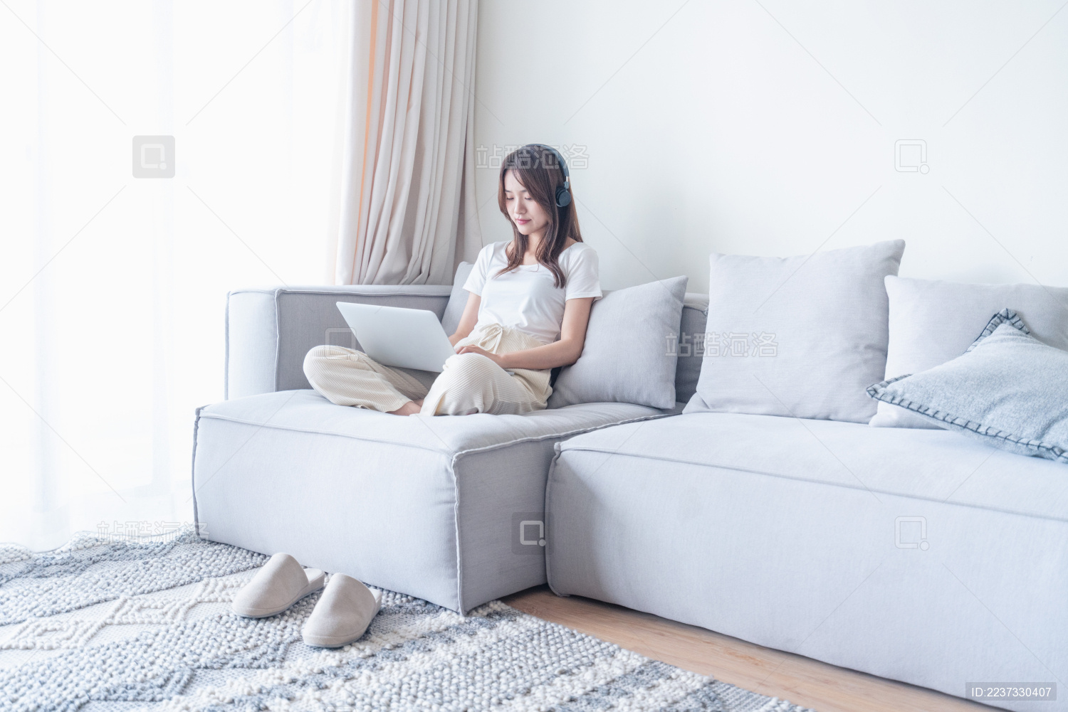 一名年轻的亚洲女子坐在客厅的沙发上使用电脑