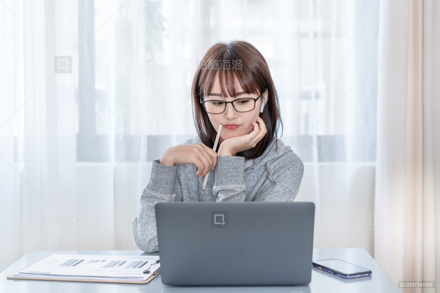 年轻女性托下巴对着电脑思考