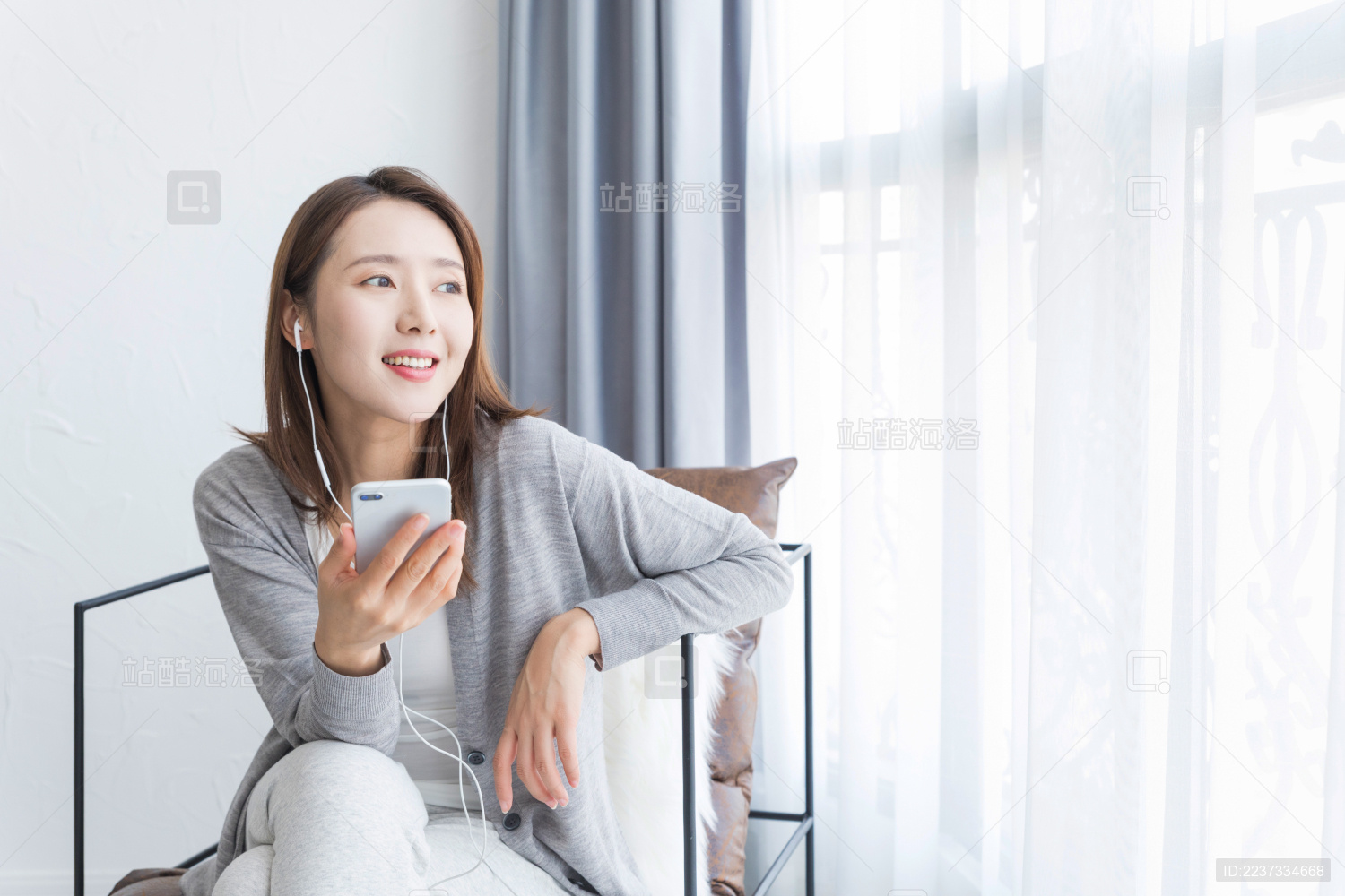 一名年轻女性坐在窗边跟别人打电话沟通