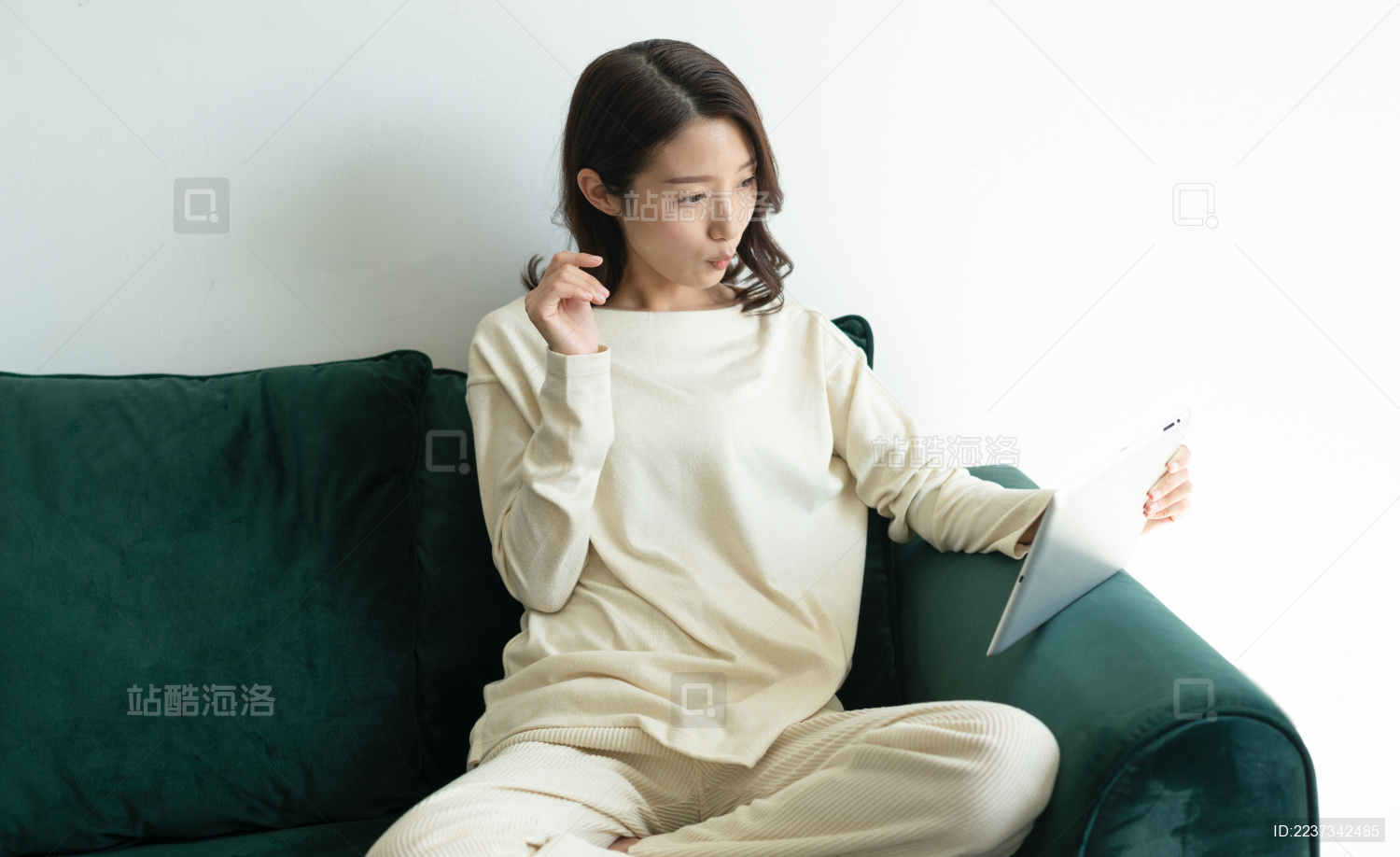 一名年轻女性在家里的客厅坐在沙发上玩平板电脑