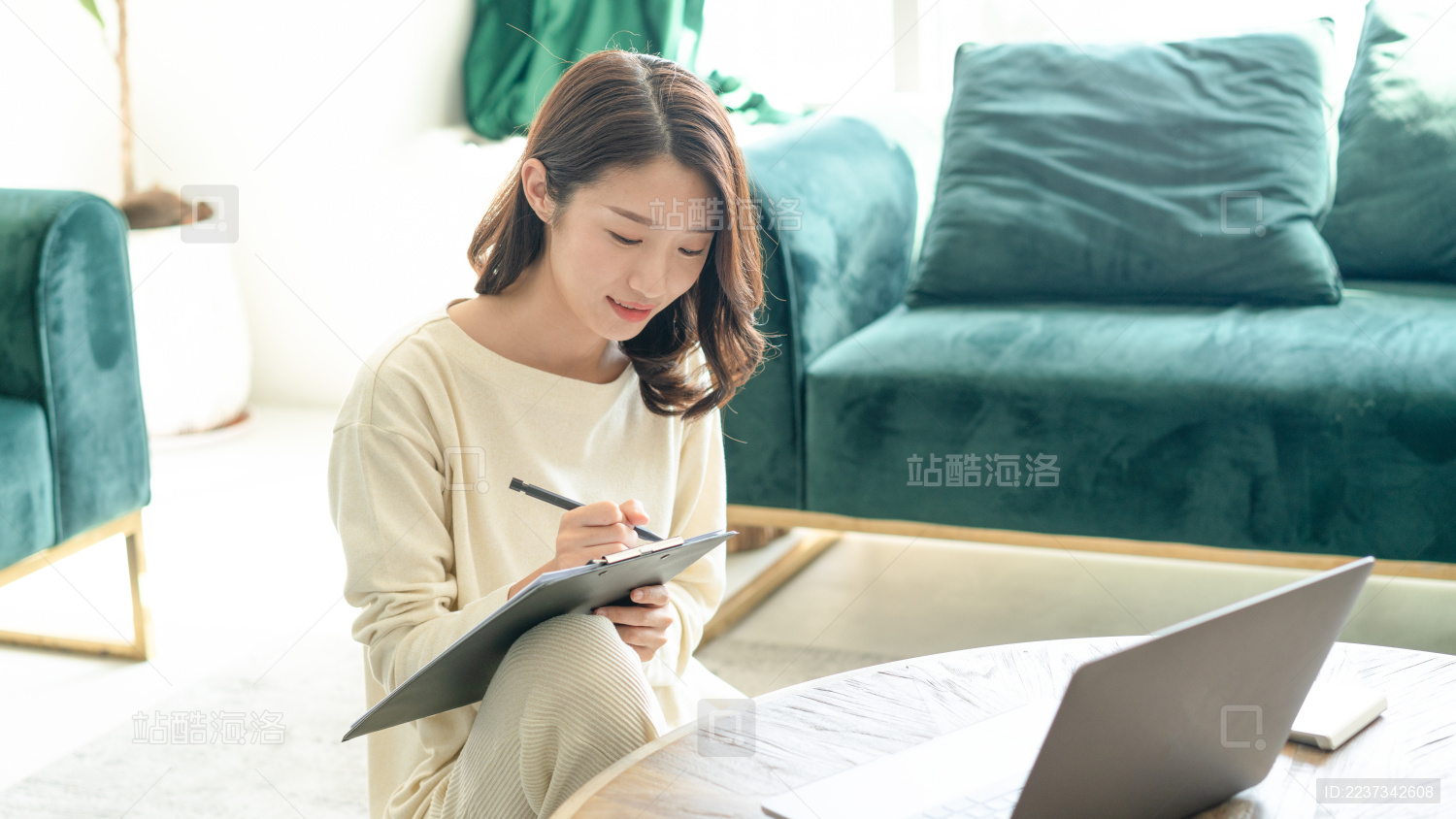 一名年轻女性在家里的客厅坐在地毯上办公