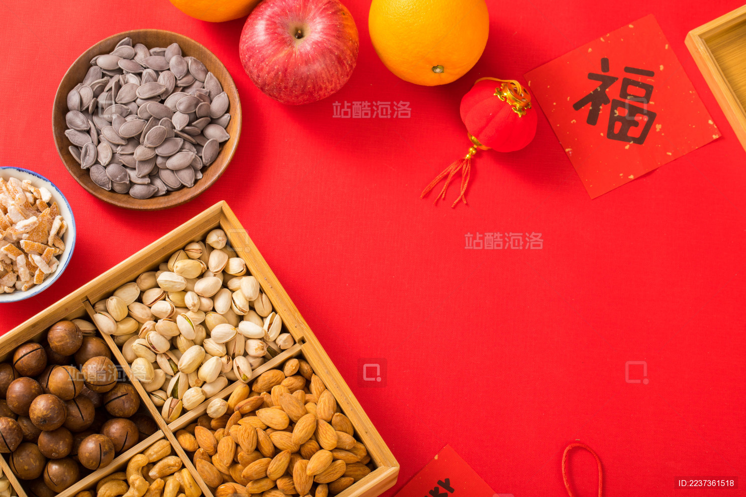 装有坚果的果盒和水果及对联放在红色背景上