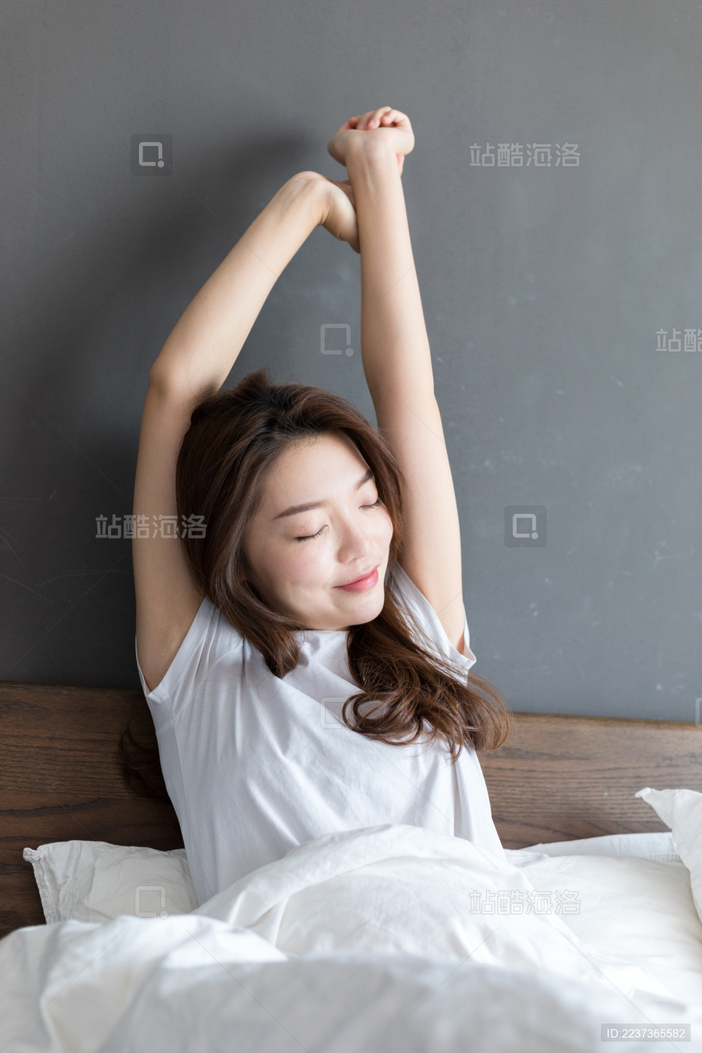 卧室里一名年轻女性在床上伸懒腰