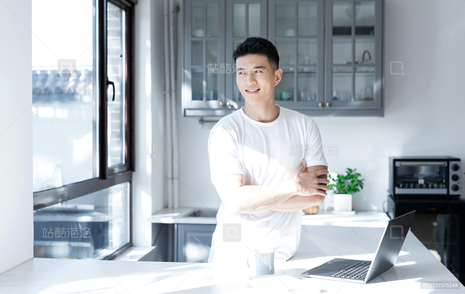 清晨站在窗边的一位亚洲年轻男性
