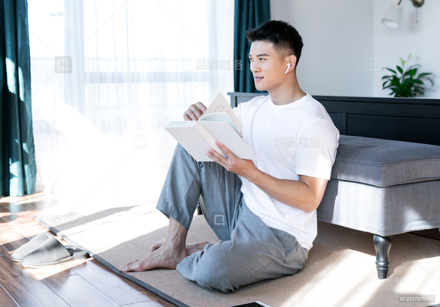 清晨在卧室读书的一位亚洲年轻男性