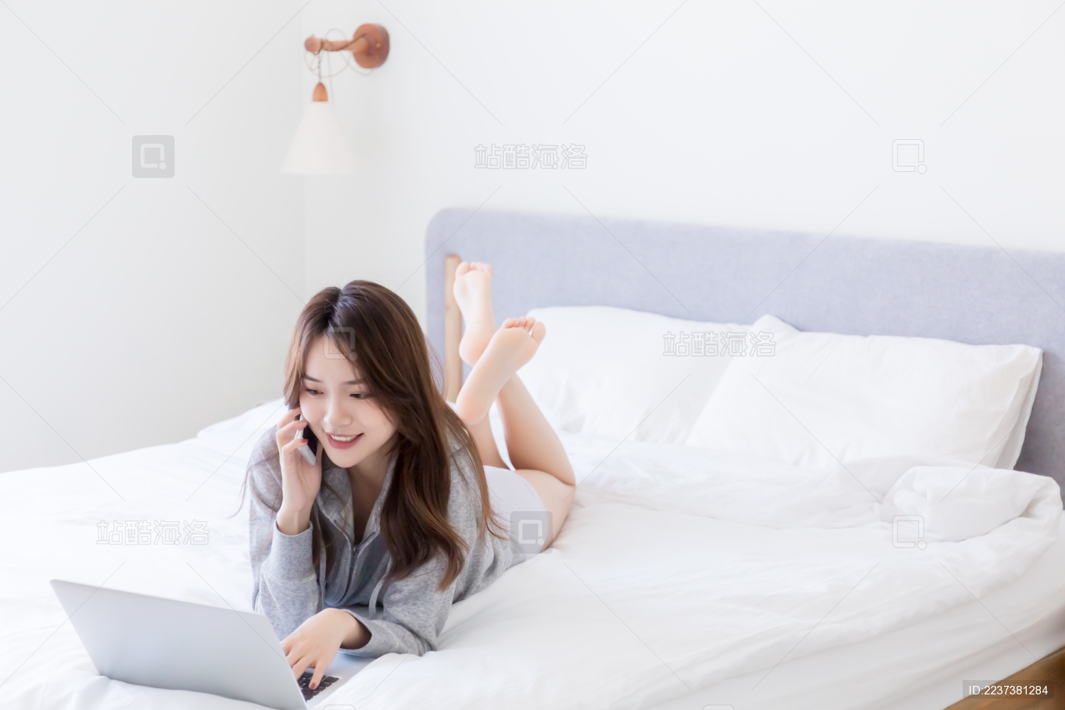 趴在床上一边打电话一边使用电脑的中国女孩