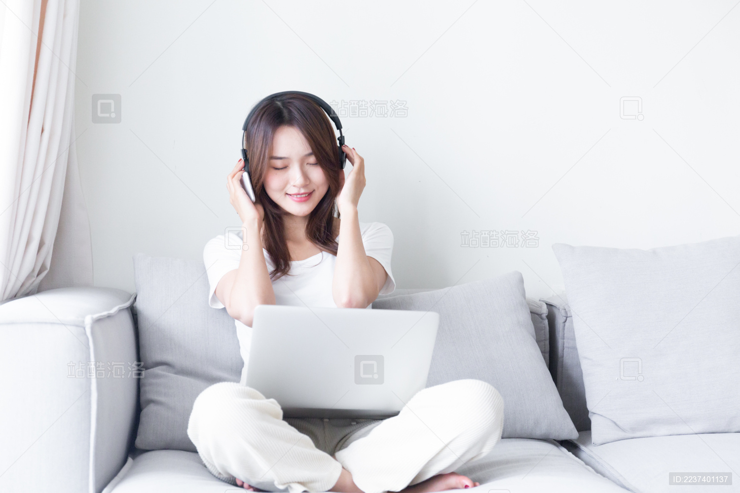 坐在沙发上听音乐的年轻女孩